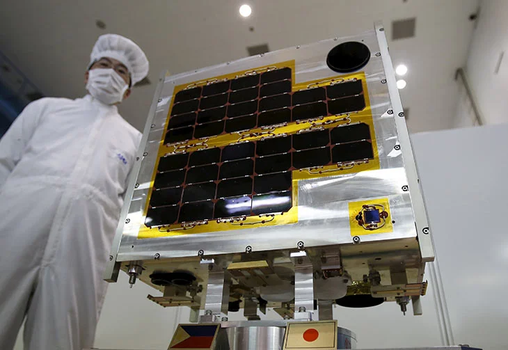 DIWATA-1, Philippines' first micro satellite for multi spectral high precision earth observation, is seen next to a staff of the Japan Aerospace Exploration Agency (JAXA) during a media tour at JAXA Tsukuba Space Center in Tsukuba, north of Tokyo, Japan, January 13, 2016. Yuya Shino, Reuters