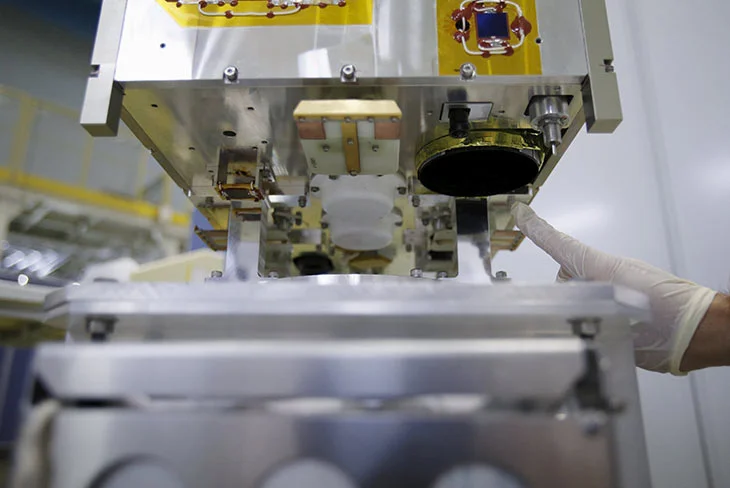 A staff of the Japan Aerospace Exploration Agency (JAXA) points at the tele lens of DIWATA-1, Philippines' first micro satellite for multi spectral high precision earth observation, during a media tour at JAXA Tsukuba Space Center in Tsukuba, north of Tokyo, Japan, January 13, 2016. Yuya Shino, Reuters
